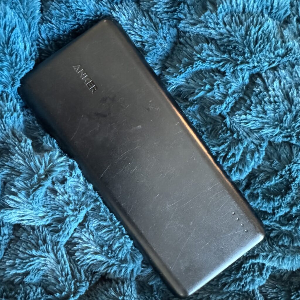 The large, black, brick-shaped charger block sits on a fuzzy blue blanket.