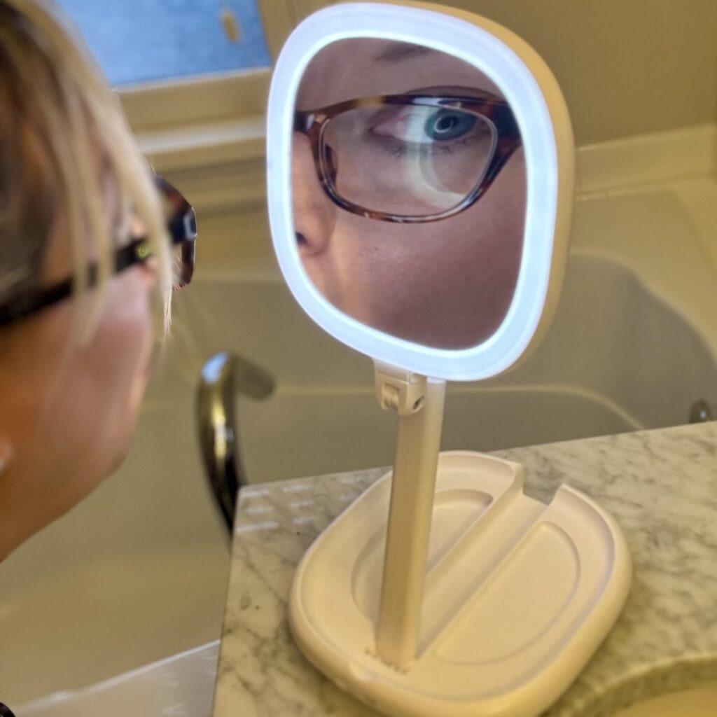 Beautifive rechargeable folding LED travel mirror with regular and magnifying sides, lightweight double-sided makeup mirror - making one of Ginny's eyes HUGE.