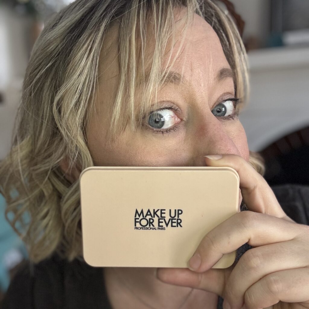 Ginny Dee holds up Make Up Forever powder foundation, showing how small this skin perfecto is.