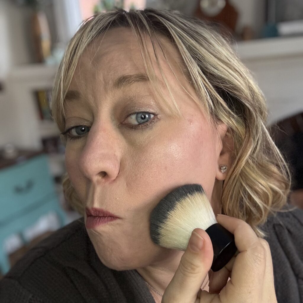 Ginny Dee uses the Elf travel kabuki brush to buff powder foundation onto her cheek for a smooth finish.