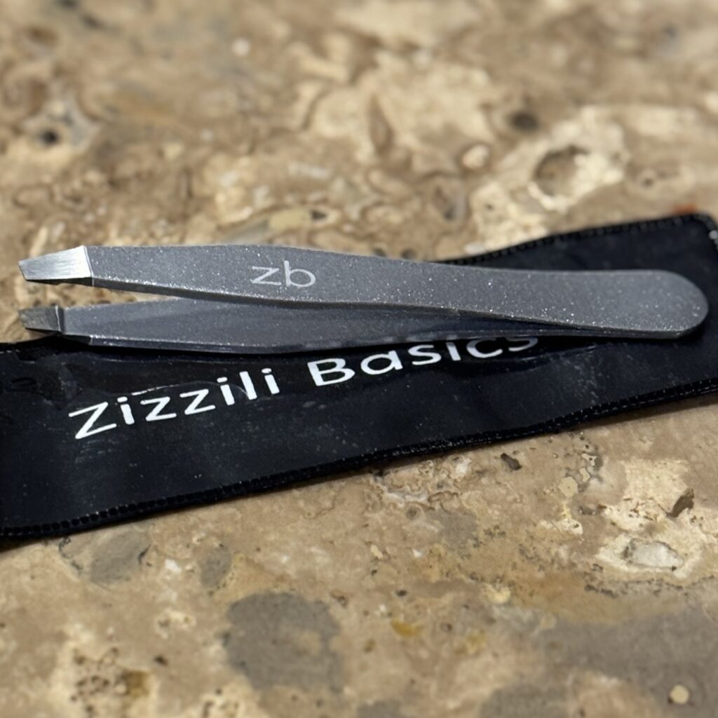 Zizzili Basics stainless steel slant tip tweezers, ready to tackle a stubborn travel-day chin hair.