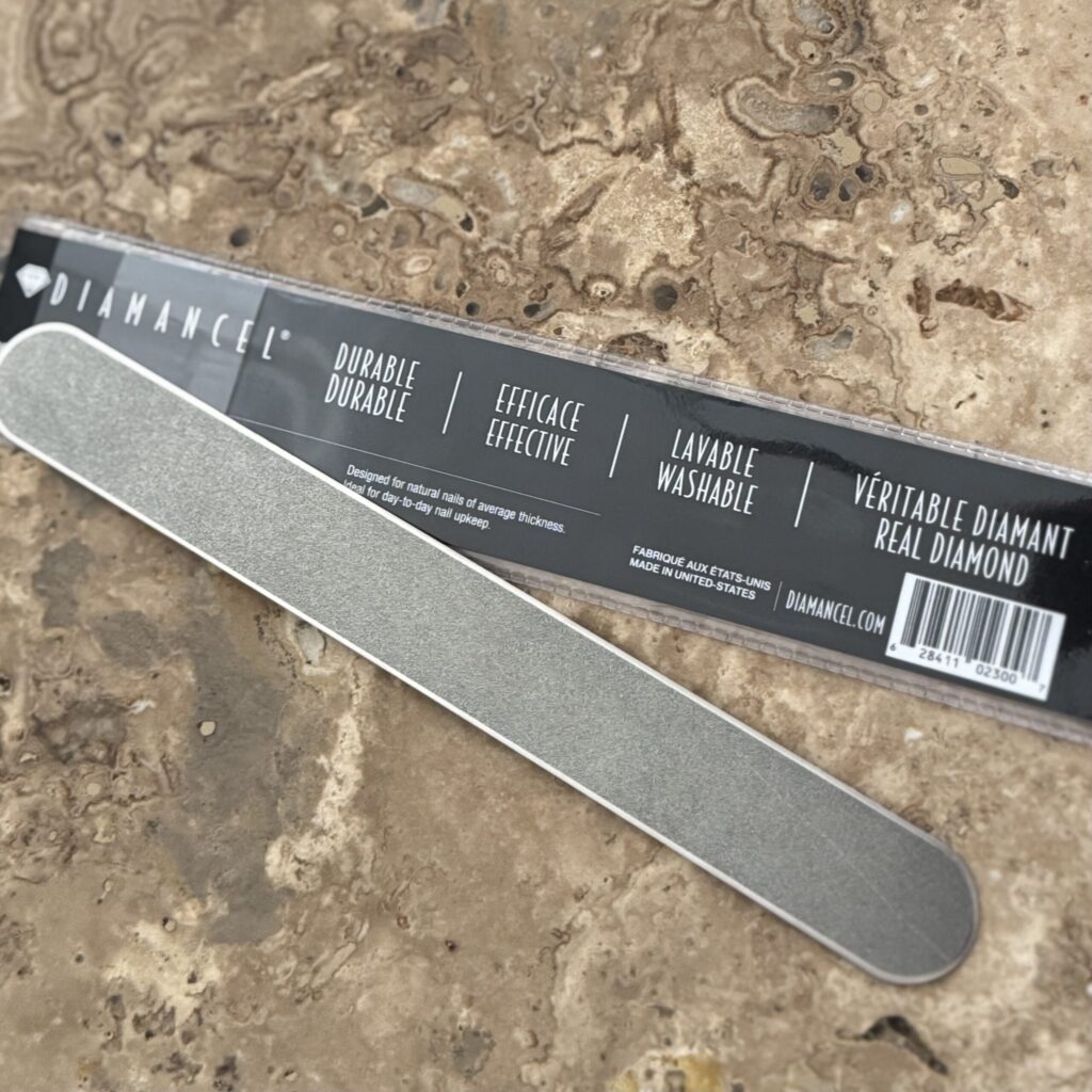 A sparkling Diamancel diamond nail file resting on a marble countertop, ready to replace bulky clippers.