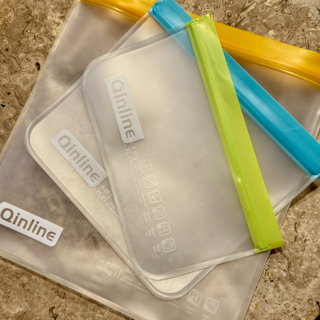 Slim, reusable silicone zip-top bags in a variety of sizes, lightweight and stacked neatly for travel convenience.