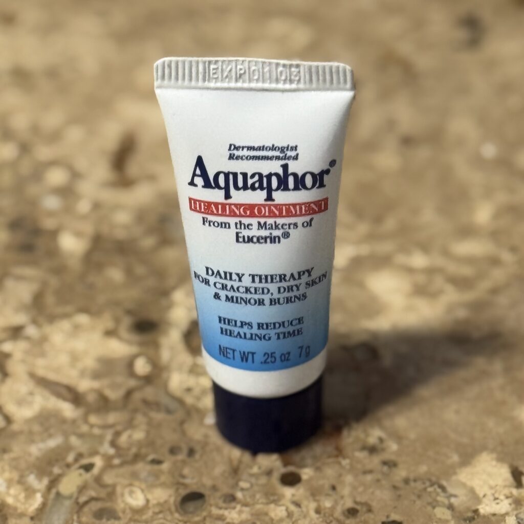 Tube of Aquaphor Healing Ointment – multi-use travel essential for lips, cuticles, and dry skin relief.