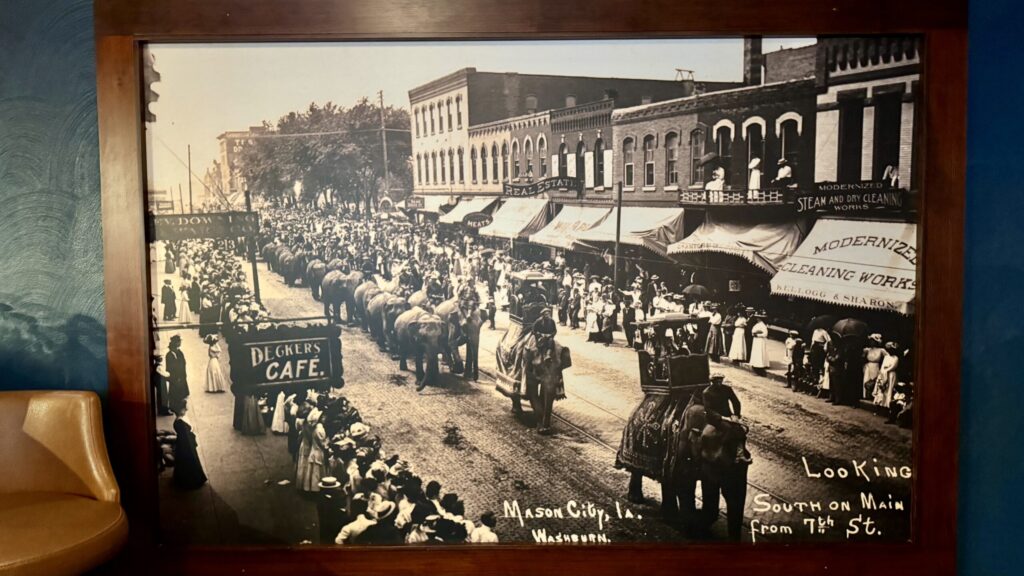 Historic parade with elephants on Main Street, Mason City (early 1900s) — captioned “Looking south on Main from 7th St.