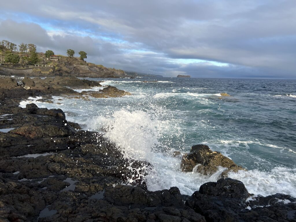 Waves crash against the jagged, volcanic shoreline on the coast of Sao Miguel Island in the Azores.