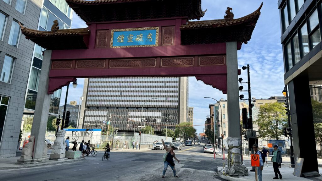 Ginny is small, but posing large, under the huge gates leading into Chinatown in Montreal.