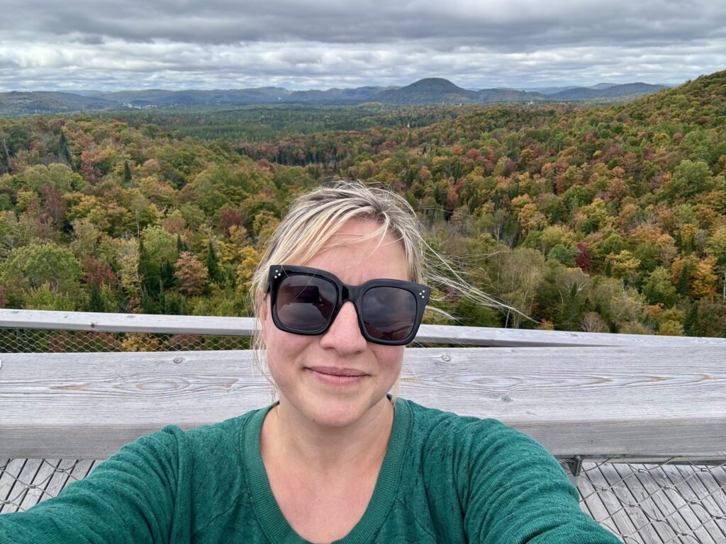 Ginny smiles from the treetops above beautiful fall foliage at Sentier des Cimas in the Laurentides outside of Montreal.