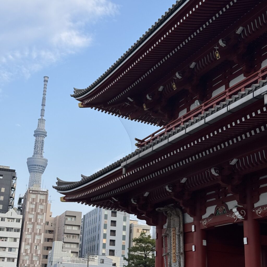 A close up view of Senso-Jï temple in Tokyo, showing the fine, ancient details, in front of skyscrapers and the Tokyo Skytree, showing the juxtaposition of old and new.
