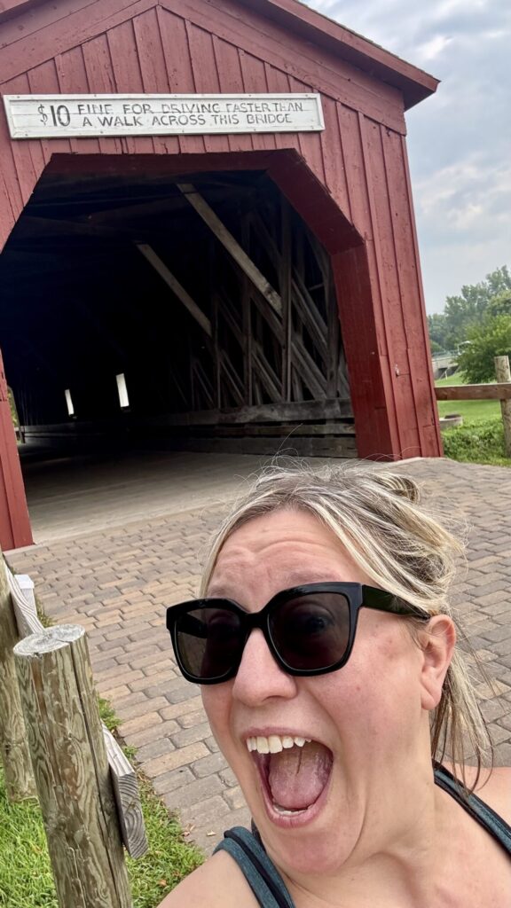 Ginny smiles in front of the last historic covered bridge in Minnesota