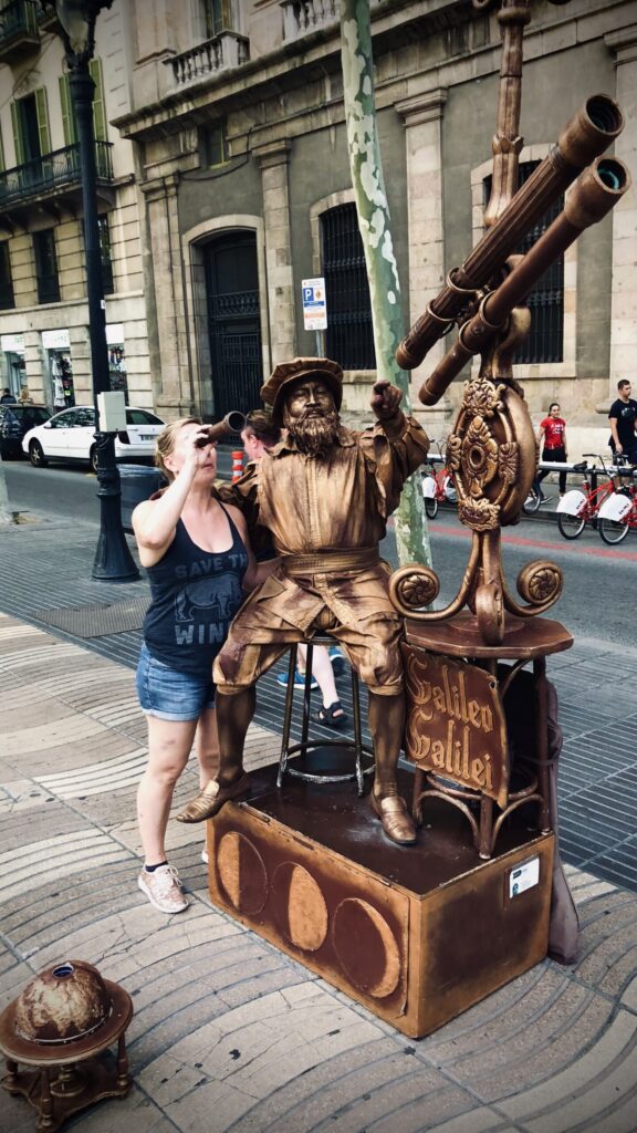 Ginny looks through a telescope next to a bronzed Galelio "statue" (street performer) in Barcelona - looking for her next adventure.